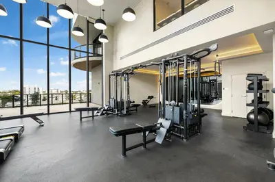 a gym with several tread machines and large windows at Luxury Miami Beach Condo At 72 Park in Miami Beach