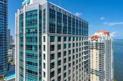 a tall white office building next to the water at Stylish 1BR Brickell Retreat Walk to Everything in Miami