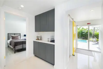 a kitchen with black cabinets and a bedroom with a bed at Chic Fort Lauderdale Getaway w/Private Heated Pool in Fort Lauderdale
