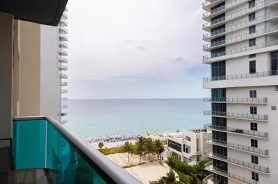a balcony with a view of the beach and a building at Beachfront 2 BR Apt Full Kitchen - No Resort Fee in Hollywood