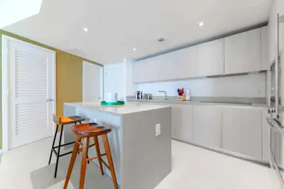 a kitchen with white cabinets and a counter and a stool at Beachfront Luxury Condo in Hollywood in Hollywood