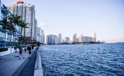 people walking on a sidewalk next to a body of water at Spacious and bright in the heart of Brickell in Miami