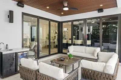 a screened in porch with white furniture and windows at Modern Zen Oasis in Design District Sleeps 16 in Miami