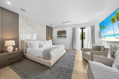 a bedroom with a white bed and a couch and a tv at Modern Zen Oasis in Design District Sleeps 16 in Miami