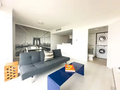 a living room with a blue couch and a washing machine at Miami top stay is nearly sold in Miami