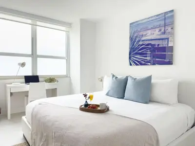 a white bedroom with a bed with a tray of fruit on it at suite with amazing bayfront views in Miami