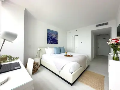 a white bedroom with a white bed and a desk at suite with amazing bayfront views in Miami