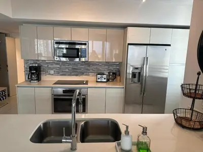 a kitchen with a sink and a stainless steel refrigerator at Family Oriented Apartments with unbelievable views in Hallandale Beach