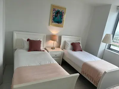 two beds in a white room with a window at Family Oriented Apartments with unbelievable views in Hallandale Beach