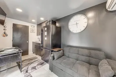 a living room with a couch and a clock on the wall at Mod Bungalow with Ultra-Private Outdoor Hang Space! in Miami Gardens