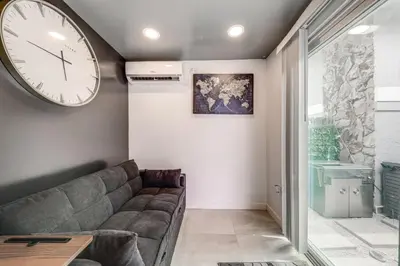 a living room with a couch and a clock on the wall at Mod Bungalow with Ultra-Private Outdoor Hang Space! in Miami Gardens