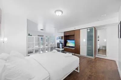 a white bedroom with a bed and a television at Cozy Ocean Drive Studio - Roof top Pool and Bar in Miami Beach
