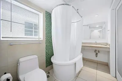 a white bathroom with a toilet and a sink at Cozy Ocean Drive Studio - Roof top Pool and Bar in Miami Beach