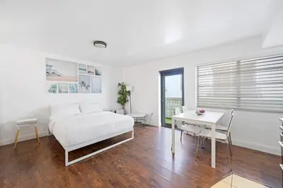 a white bedroom with a bed and a table at Cozy Ocean Drive Studio - Roof top Pool and Bar in Miami Beach