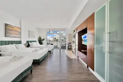 a hotel room with white beds and a flat screen tv at Stylish Studio in South Beach with Ocean Views in Miami Beach
