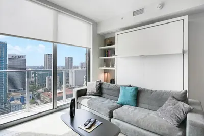 a living room with a couch and a large window at Luxury Condo w Rooftop Pool & Gym in Miami