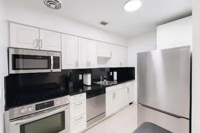 a kitchen with white cabinets and a stainless steel refrigerator at Stylish 2BR Getaway - Prime Miami Location in Miami