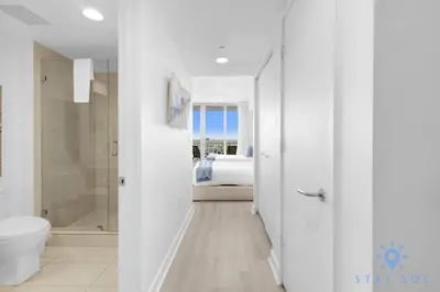 a white bathroom with a bed and a toilet at Infinite Views - Private Balcony -Poolside Bliss Near the Beach in Hallandale Beach