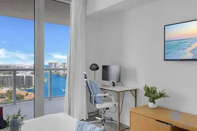 a bedroom with a desk with a computer and a window at Infinite Views - Private Balcony -Poolside Bliss Near the Beach in Hallandale Beach