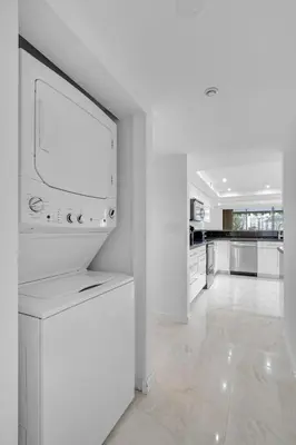 a white kitchen with a large tv on a wall at Waterfront 3bed | Pool | 10min walk to Beach in Hallandale Beach