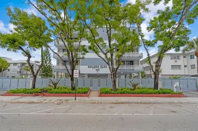 a white building with trees in front of a street at Waterfront 3bed | Pool | 10min walk to Beach in Hallandale Beach