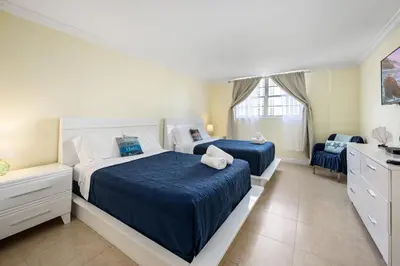 a bedroom with two beds and a chair in it at Bright Stylish 2BR Condo Stunning View Of Ocean in Sunny Isles Beach
