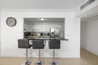 a kitchen with a counter with three bar stools at Bright Stylish 2BR Condo Stunning View Of Ocean in Sunny Isles Beach