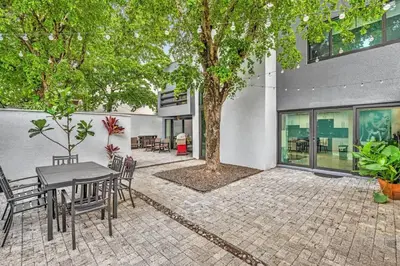 a patio with a table and chairs and a tree at Coconut Grove Haven Family in Miami