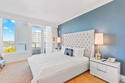 a bedroom with a white bed and a blue wall at Luxury Condo at Trésor Miami Beach in Miami Beach