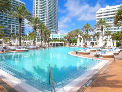 a large swimming pool with palm trees and buildings at Luxury Condo at Trésor Miami Beach in Miami Beach