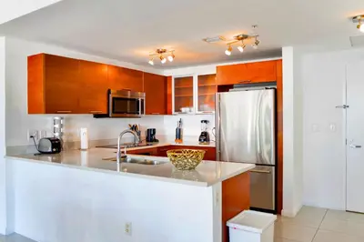 a kitchen with wooden cabinets and a stainless steel refrigerator at Miami Midblock Condo - City Views, Pool & Balcony! in Miami