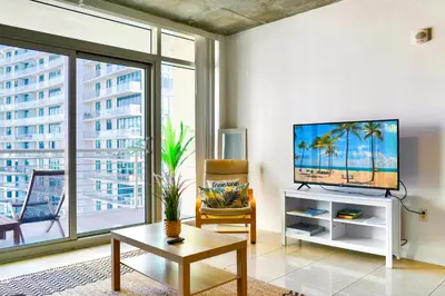 a living room with a tv and a large window at Miami Midblock Condo - City Views, Pool & Balcony! in Miami