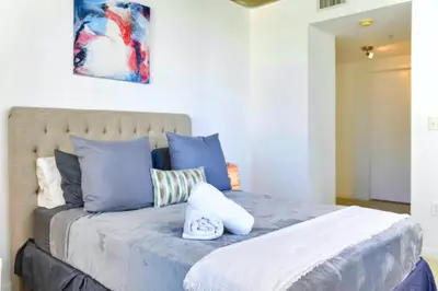 a bedroom with a large bed with blue pillows at Miami Midblock Condo - City Views, Pool & Balcony! in Miami