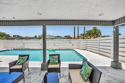 a swimming pool with two chairs and a table at 4BR Home Heated Pool And BBQ short drive Beach! in Hollywood
