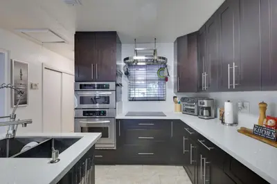 a kitchen with dark wood cabinets and stainless steel appliances at Lakefront Getaway with Dock Near Las Olas Beach in Fort Lauderdale