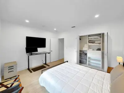 a bedroom with a bed and a desk and a television at Brickell, Remote-Ready Oasis in Miami