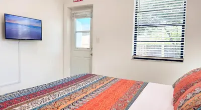 a bedroom with a bed and a tv on a wall at The Chill Pill - Wilton Drive and Jacuzzi in Fort Lauderdale
