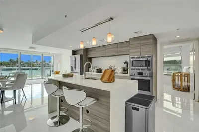 a kitchen with a white counter and chairs in it at Beachfront Bliss in Miami in Miami Beach