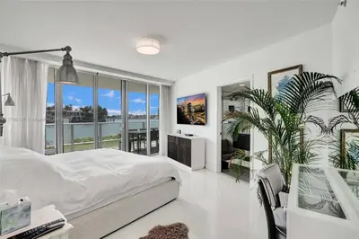 a white bedroom with a bed and a large window at Beachfront Bliss in Miami in Miami Beach