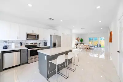 a kitchen with white cabinets and a table and chairs at Family-Friendly Townhouse w Private Parking Included in Miami