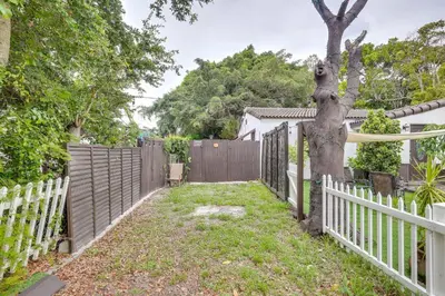 a white fence and a tree in a yard at 3 Mi to Beach Hollywood Studio with Yard! in Hollywood