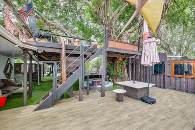 a house with a staircase and an umbrella at 3 Mi to Beach Hollywood Treehouse with Deck and Yard! in Hollywood