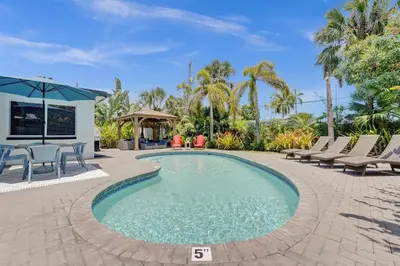a swimming pool with chairs and a table at NEW! Private Oasis with Heated Pool Minutes to Wilton Dr and the Beach in Fort Lauderdale