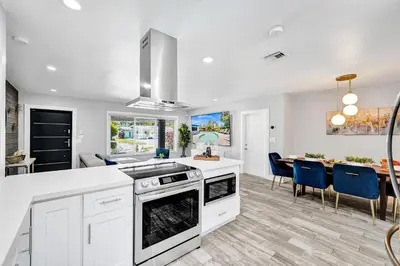 a kitchen with white cabinets and a dining room at NEW! Private Oasis with Heated Pool Minutes to Wilton Dr and the Beach in Fort Lauderdale