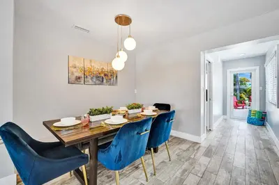 a dining room with a wooden table and blue chairs at NEW! Private Oasis with Heated Pool Minutes to Wilton Dr and the Beach in Fort Lauderdale