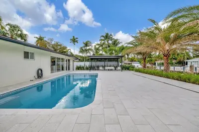 a swimming pool in the backyard of a house with palm trees at Waterfront Oasis with Private Pool in Fort Lauderdale