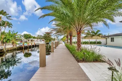 a walkway next to a canal with palm trees at Waterfront Oasis with Private Pool in Fort Lauderdale