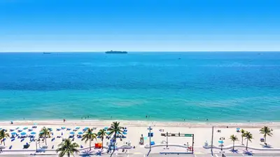 a beach with umbrellas and palm trees and the ocean at Tiffany Shoreline - PH Floor, Ocean View, Walk to beach in Fort Lauderdale