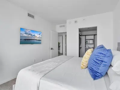 a white bedroom with a large bed with blue pillows at X Lounge VI-Premium Corner Residence in Miami
