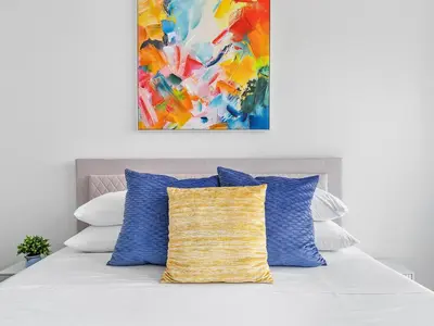 a painting hangs above a bed with blue pillows at X Lounge VI-Premium Corner Residence in Miami